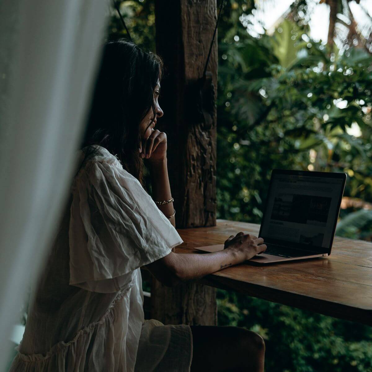 women in front of her laptop thinking with jungle as backdrop in Ubud, Bali